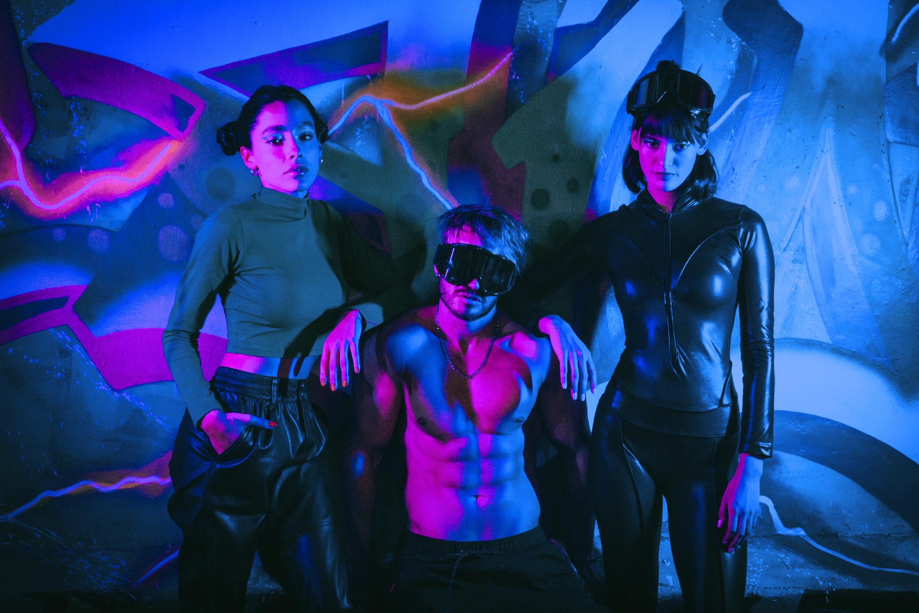 Queer group posed against a blue and magenta wall